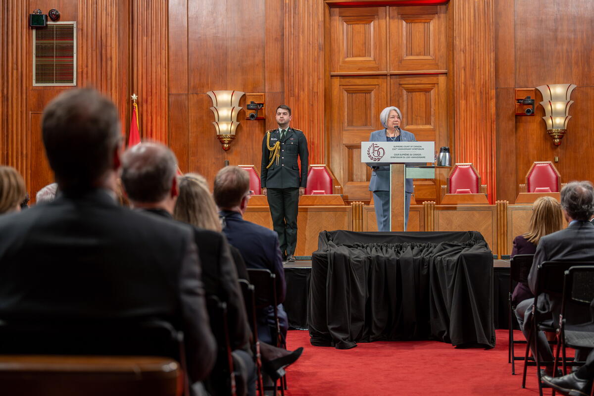 La gouverneure générale Mary Simon debout sur un pupitre à l'intérieur de la Cour suprême du Canada. Un aide-de-camp se tient à sa droite.