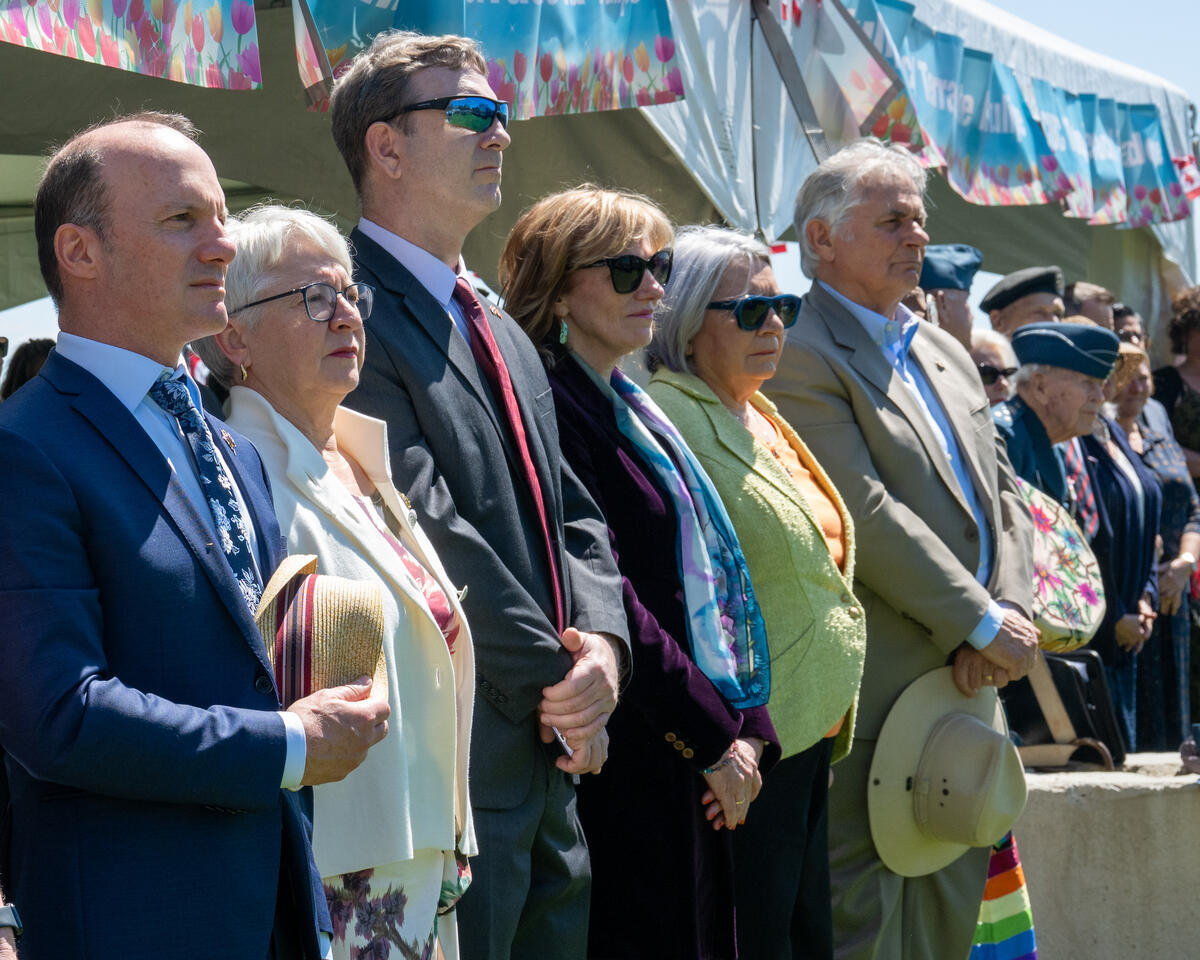 Governor General Mary Simon and Mr. Whit Fraser standing with a row of people outside for the opening ceremony of the Canadian Tulip Festival.