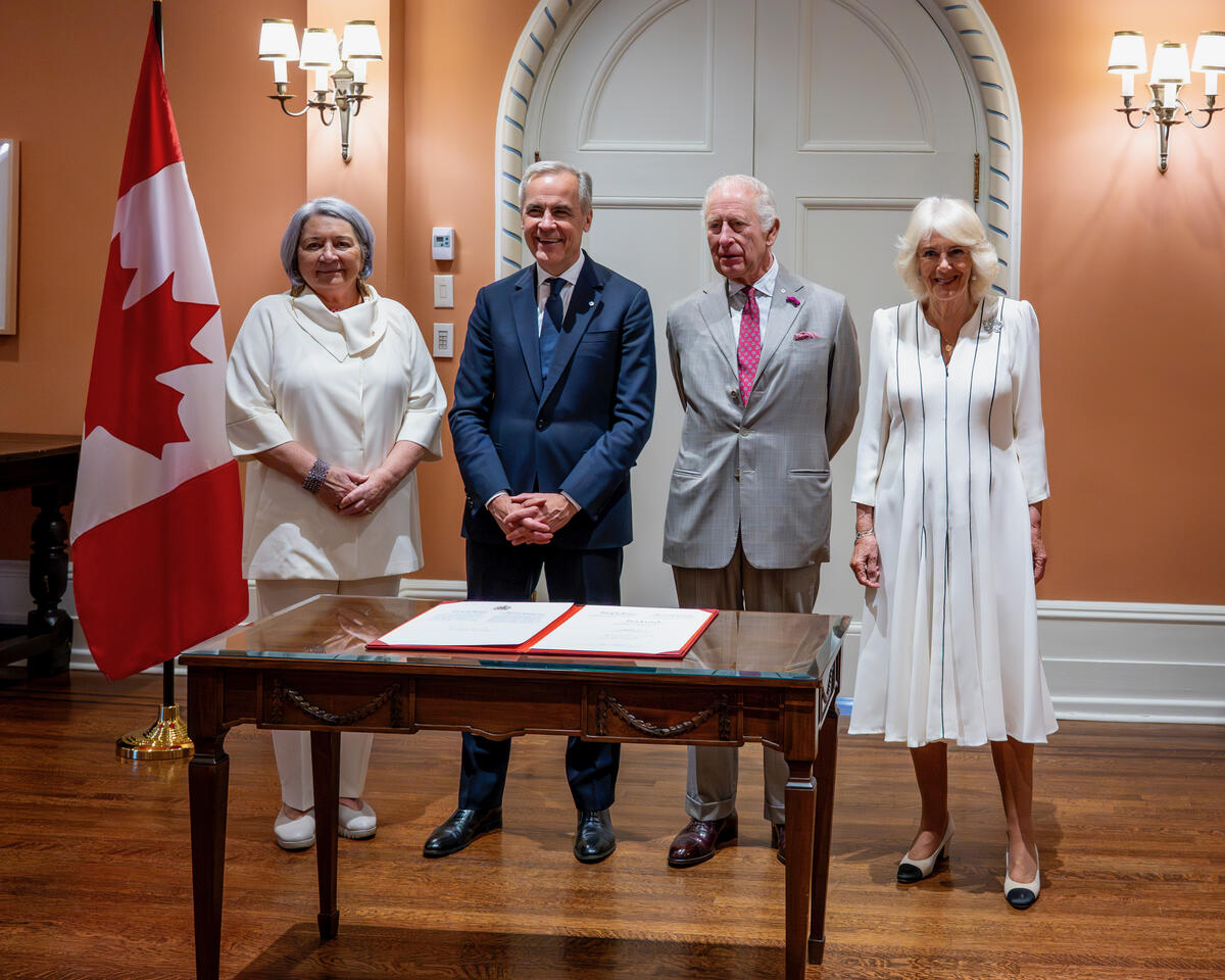 Governor General Mary Simon, Prime Minister Mark Carney and Their Majesties standing in front of a table.