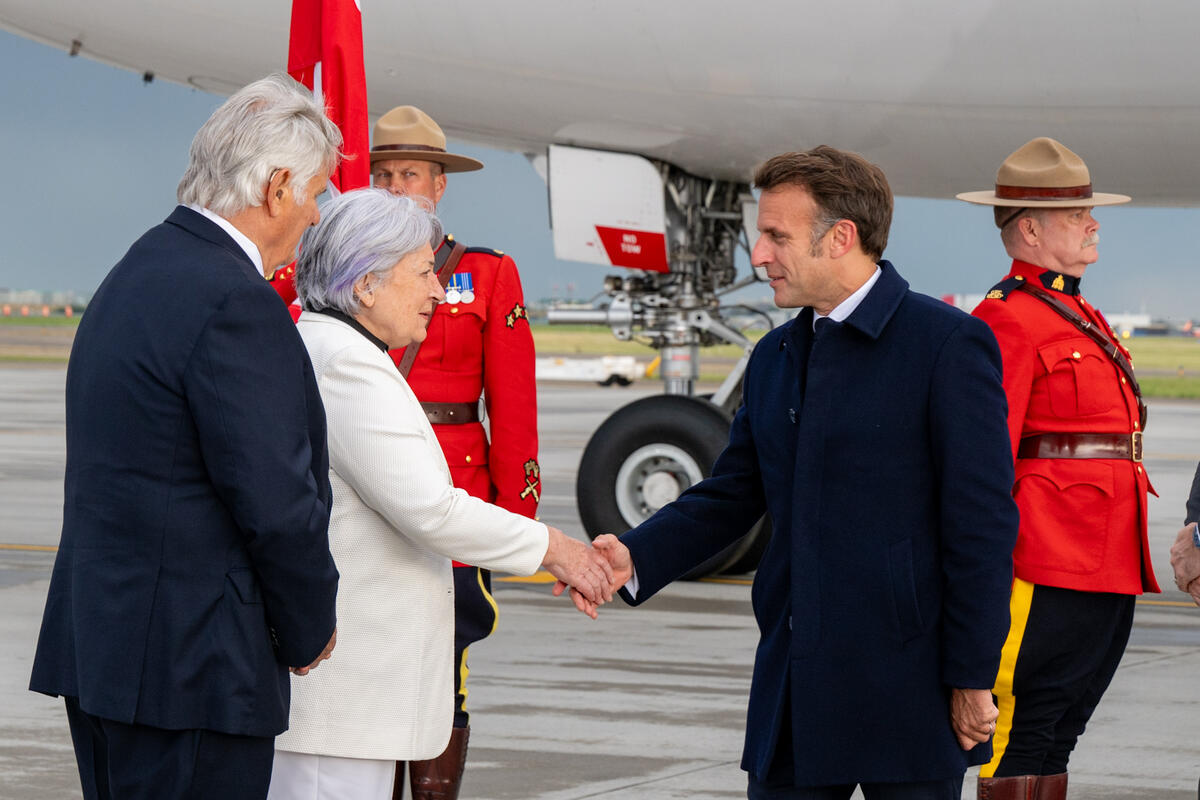 Governor General Mary Simon shaking hands with President Emmanuel Macron at the airport.