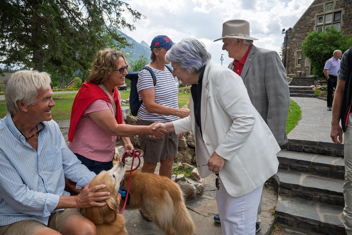 Their Excellencies shaking hands with people at Banff National Park. A person has two dogs on leash.