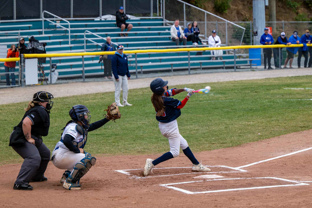 An baseball player hitting the ball at the home plate.