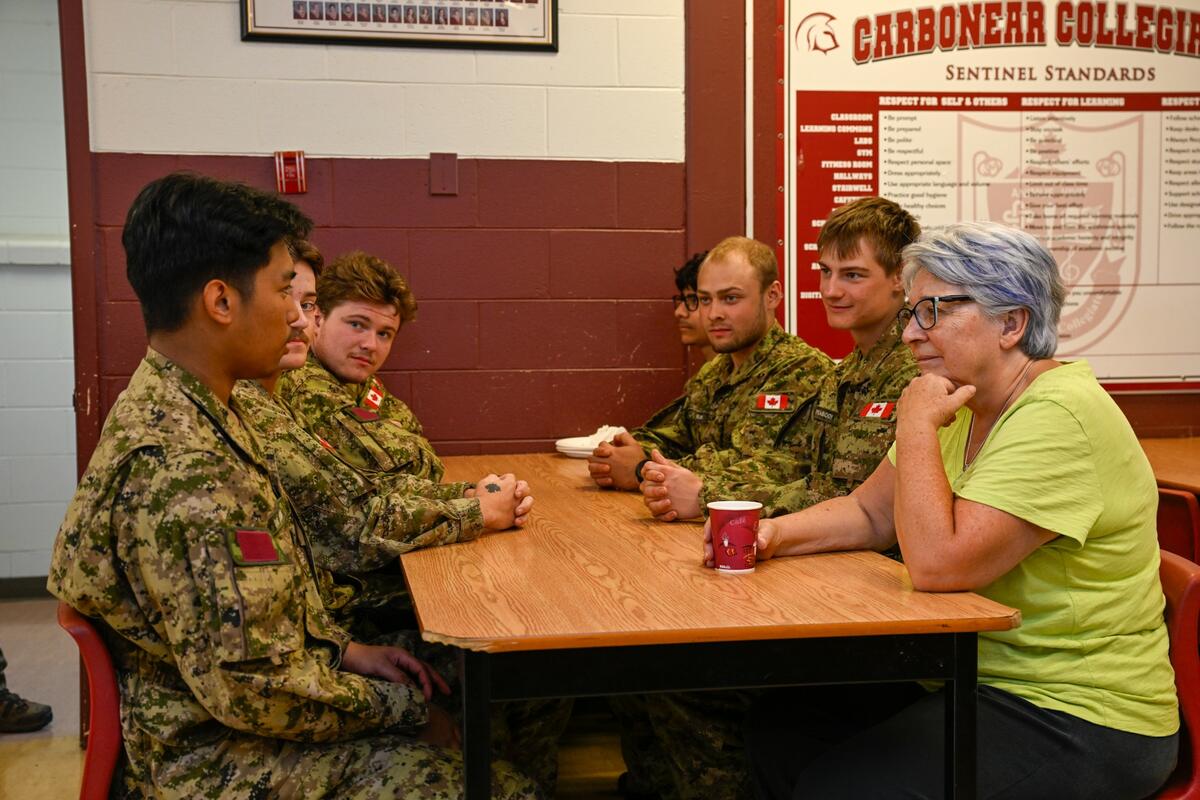 La gouverneure générale Mary Simon assise à une table avec des membres des Forces armées canadiennes.