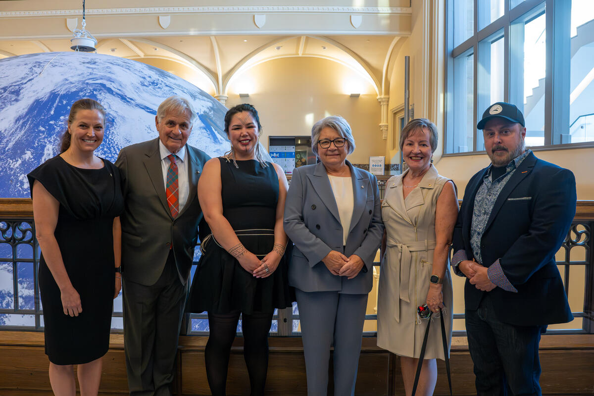 La gouverneure générale Mary Simon et M. Whit Fraser posant pour une photo avec quatre autres personnes à l'intérieur du Musée de la nature.