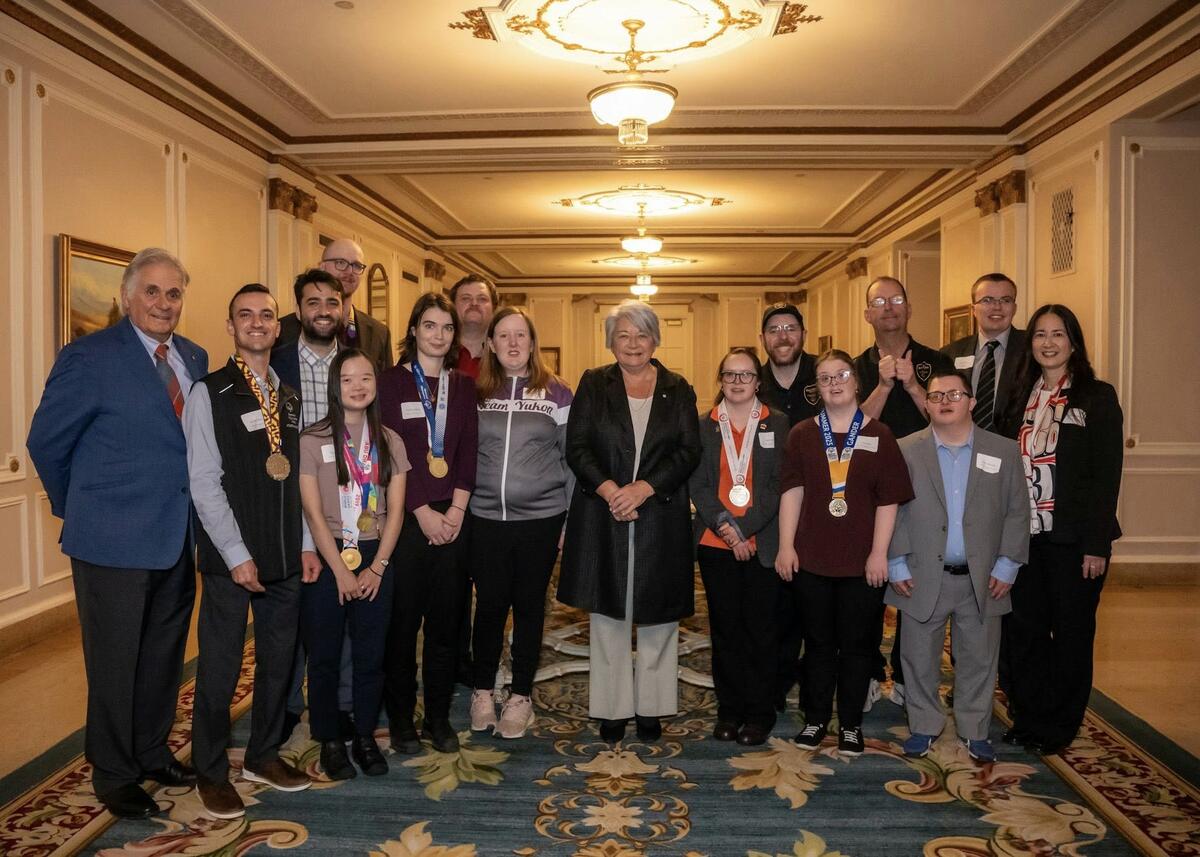 Governor General Mary Simon posing with a group of people involved in the Special Olympics. Several people are wearing medals.