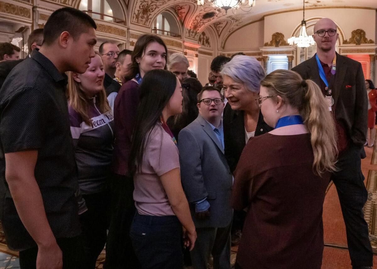 Governor General Mary Simon speaking to a group of people. They are in an ornate hall with chandeliers and detailed archways.