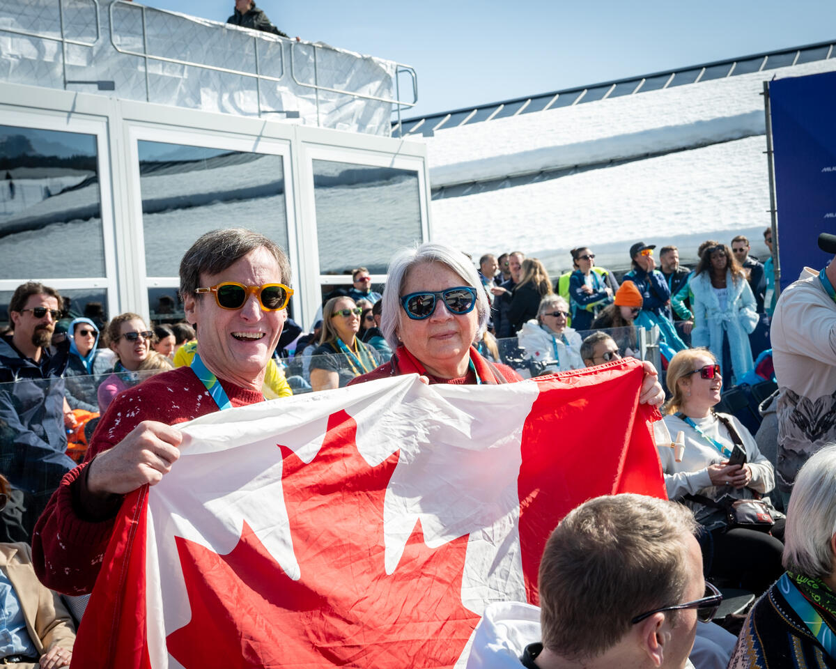  Governor General Mary Simon holding a large Canada flag with another person in the stands.