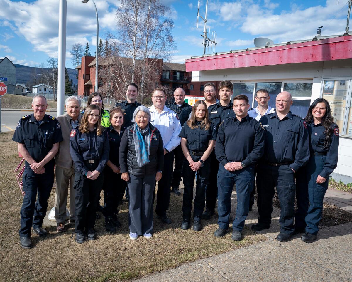 Governor General Mary Simon and Mr. Whit Fraser posing for a photo outside with Tumbler Ridge first responders.