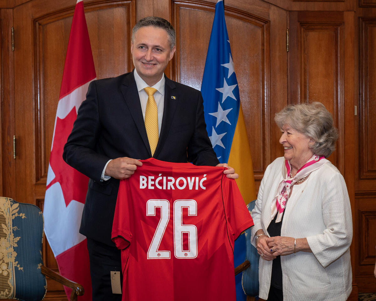 His Excellency Denis Bećirović, Chairman of the Presidency of Bosnia and Herzegovina holding a red jersey with the name "Bećirović" and the number 26 on it. Governor General Louise Arbour is smiling next to him.
