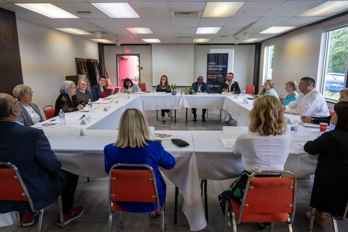 Governor General Simon and a group of people seated at rectangular tables in the shape of a square.