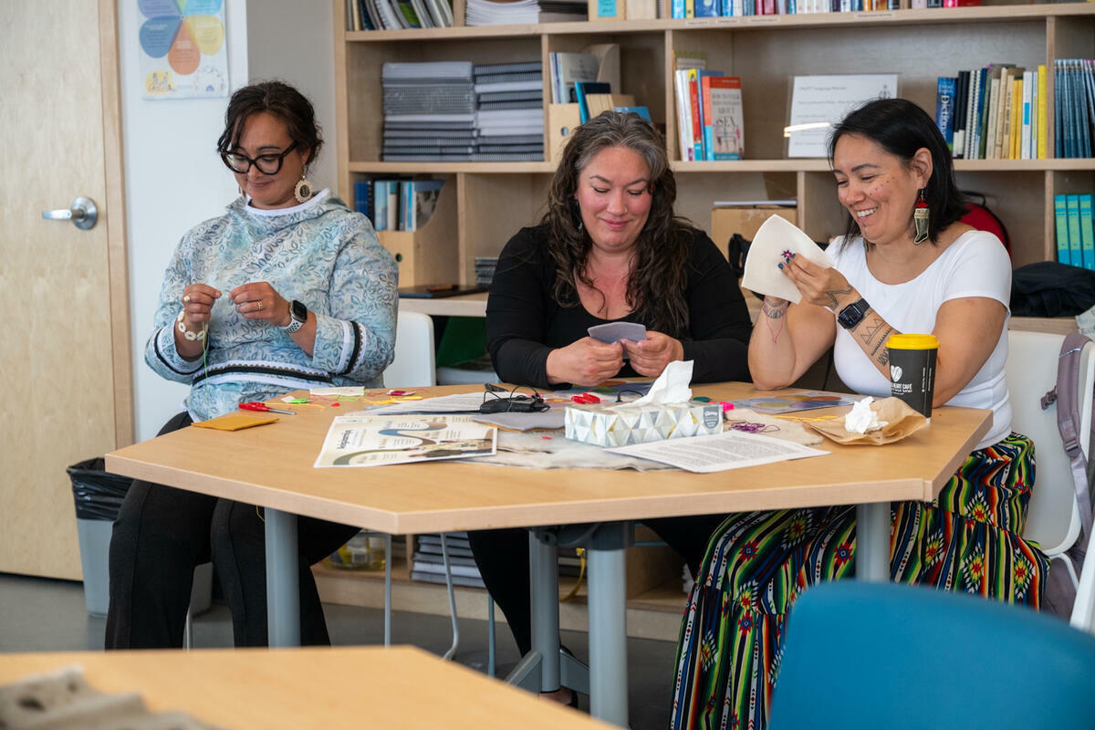 Three individuals smiling and participating in a workshop at the Inuusirvik Community Wellness Hub.