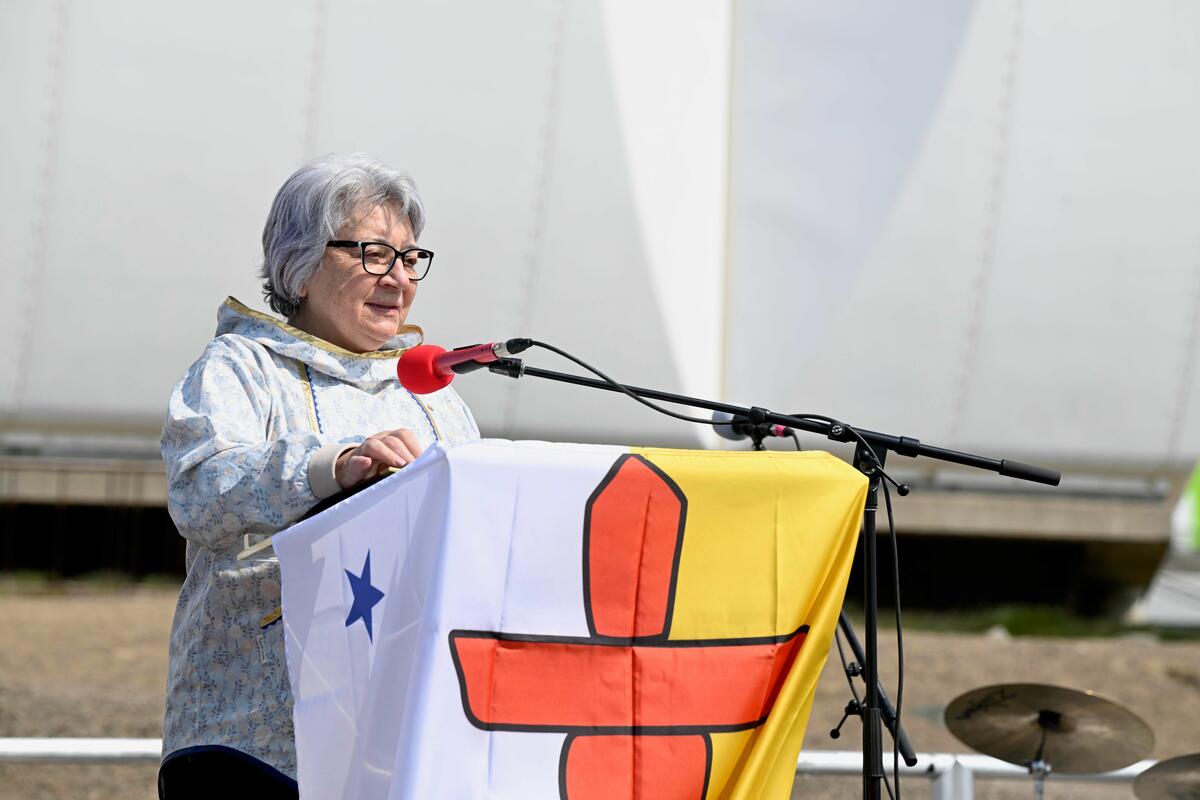 La gouverneure générale Mary Simon debout devant une tribune drapée du drapeau du Nunavut.