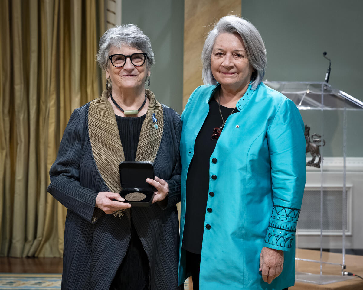 Governor General Mary Simons is posing with a lady who is holding an opened award medal case.