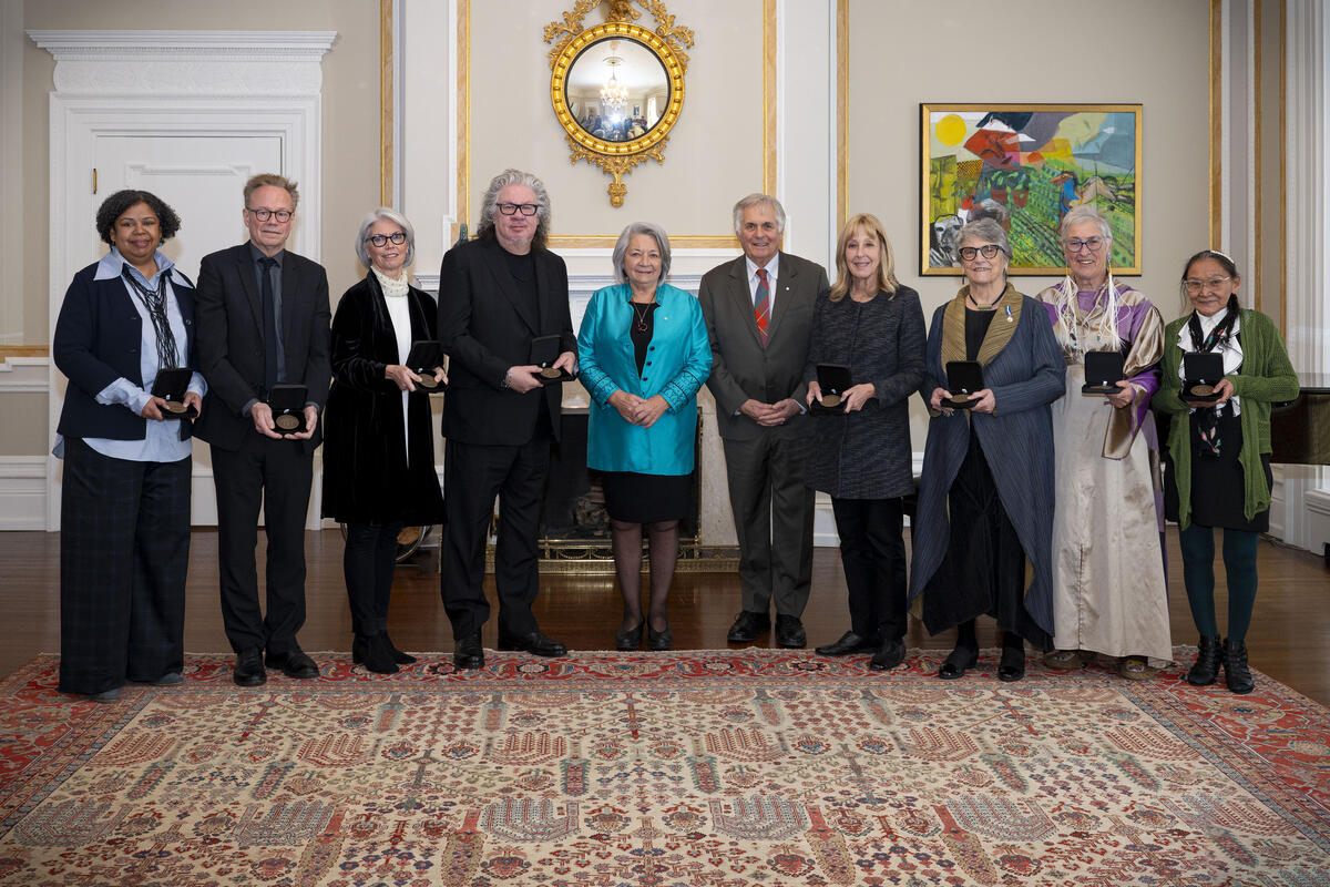 A group of people poses for the camera. Governor General Mary Simon and Mr. Whit Fraser are in the centre.