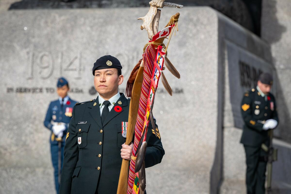 An Indigenous military member is walking in front of the National War Memorial in Ottawa.