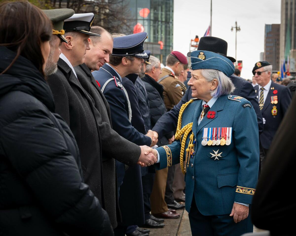 Governor General Mary Simon, wearing the Air Force uniform, is shaking hands with a participant to the Remembrance Day ceremony.