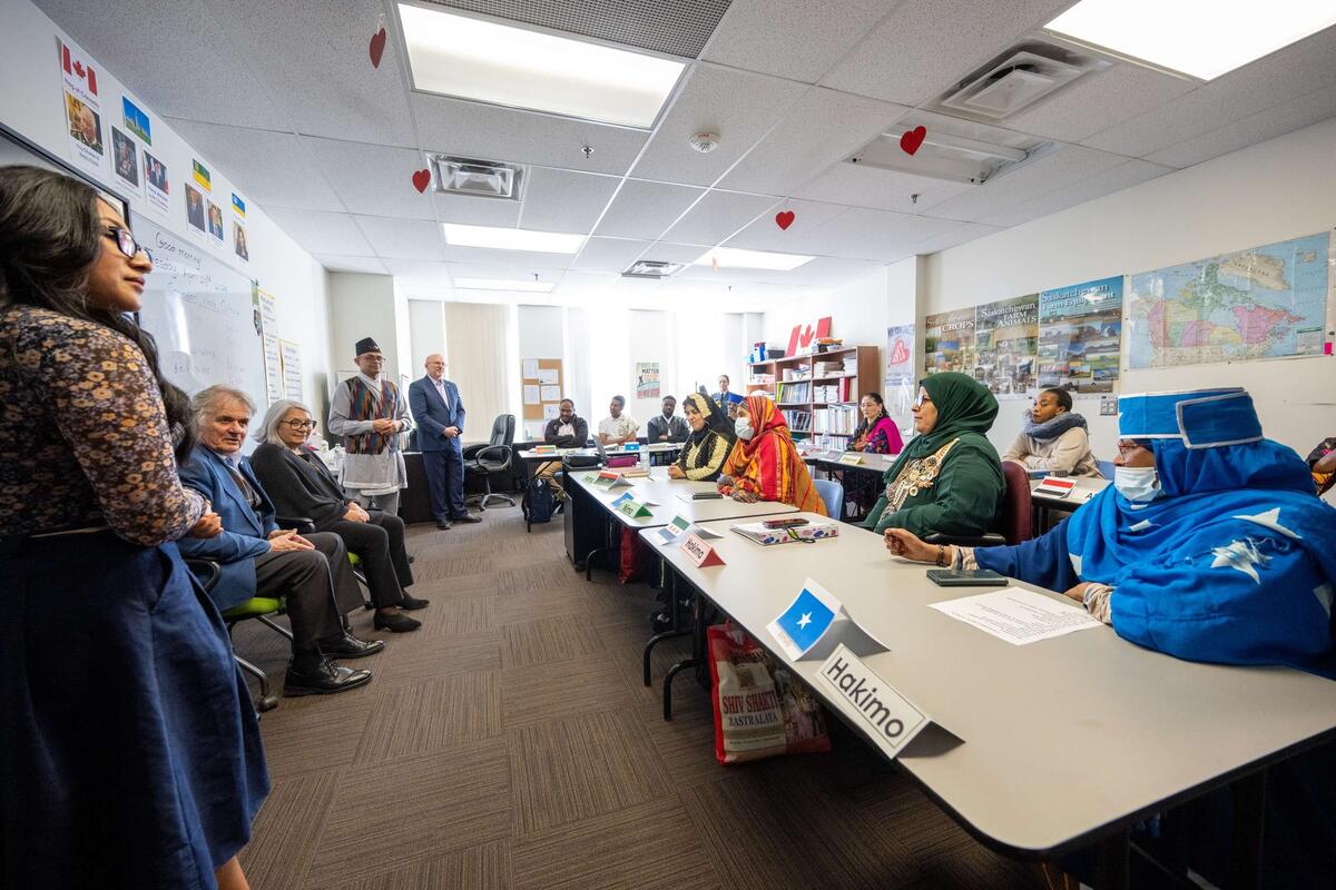 La gouverneure générale Simon assise à l'avant d'une salle de classe, face à des personnes assises à des pupitres.