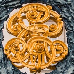 Portail de fer forgé noir à pointes dorées, orné d’un emblème composé de lettres d’or ceintes de lauriers et surmontées d’une couronne.