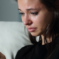 A girl holds her phone while crying