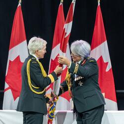 La gouverneure générale Mary Simon remet le pavillon des Forces armées canadiennes au général Jennie Carignan. Le général Wayne Eyre se tient derrière elle.