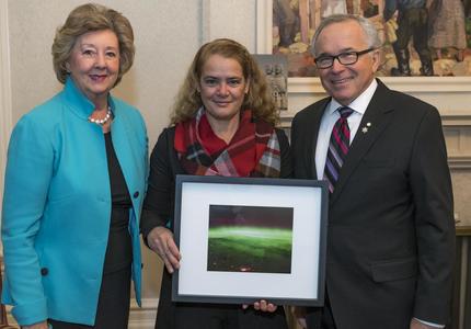 La gouverneure générale, tenant une photo prise de l'espace, est début entre  Leurs Honneurs l'honorable Janice C. Filmon, lieutenant-gouverneur du Manitoba, et l'honorable Gary Albert Filmon.