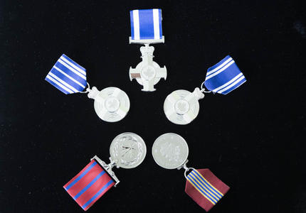 Une photo des différentes médailles remises aux récipiendaires lors de la cérémonie d'honneur à thème militaire.