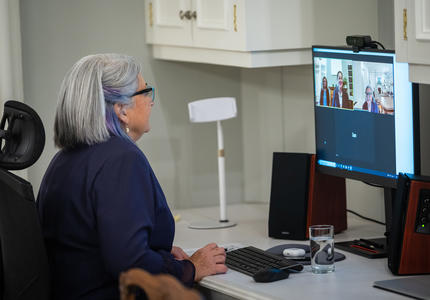 La gouverneure générale participe à un appel virtuel sur son ordinateur. Elle est assise à un bureau. Nous pouvons la voir, ainsi qu'une autre femme, sur l'écran de son ordinateur.