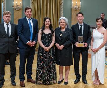 La Gouverneure générale Simon se tient aux côtés d'un groupe de lauréats du Prix Michener. Ils se trouvent dans la salle de bal de Rideau Hall.