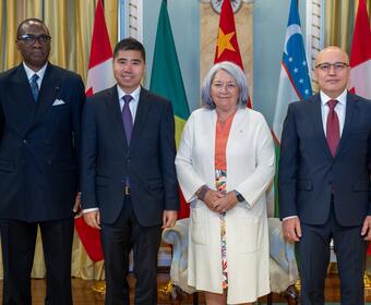 Governor General Mary Simon stands with the new heads of mission in front of their flags