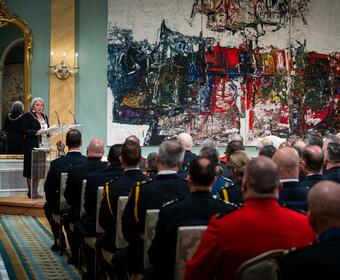 La gouverneure générale Mary Simon s'exprime sur un podium dans la salle de bal de Rideau Hall. Elle regarde une foule de récipiendaires de l'Ordre du mérite des corps policiers. Les récipiendaires portent des uniformes de police.