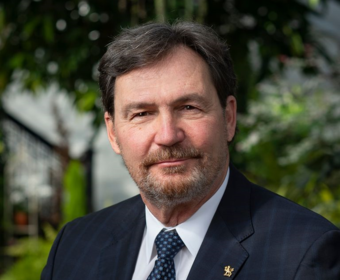 The Administrator is sitting outside; he is smiling at the camera. 