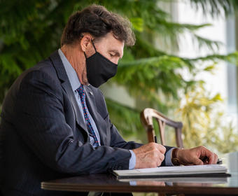 The Administrator sitting a desk signing a document.