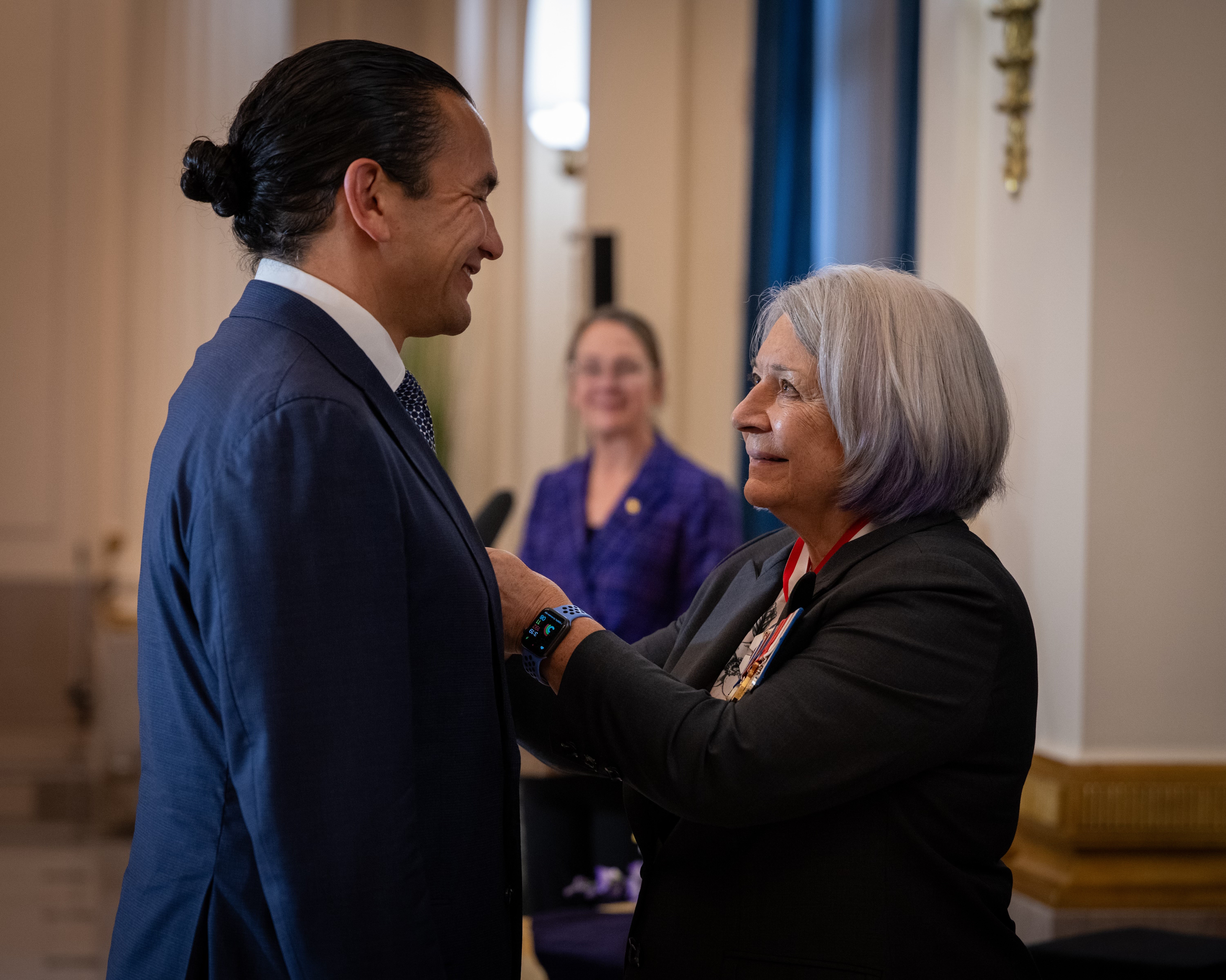 La gouverneure générale Simon sourit au premier ministre Wab Kinew en installant une médaille du couronnement à son veston.