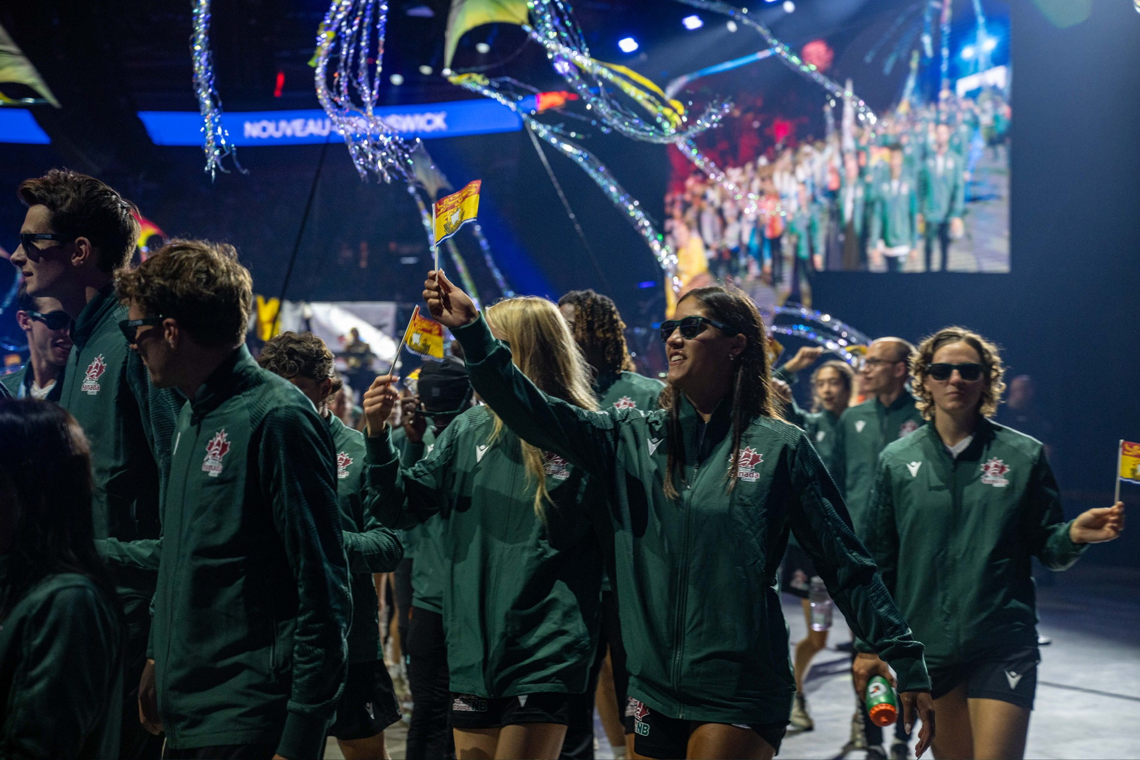 Teams participating in a parade in a large stadium.